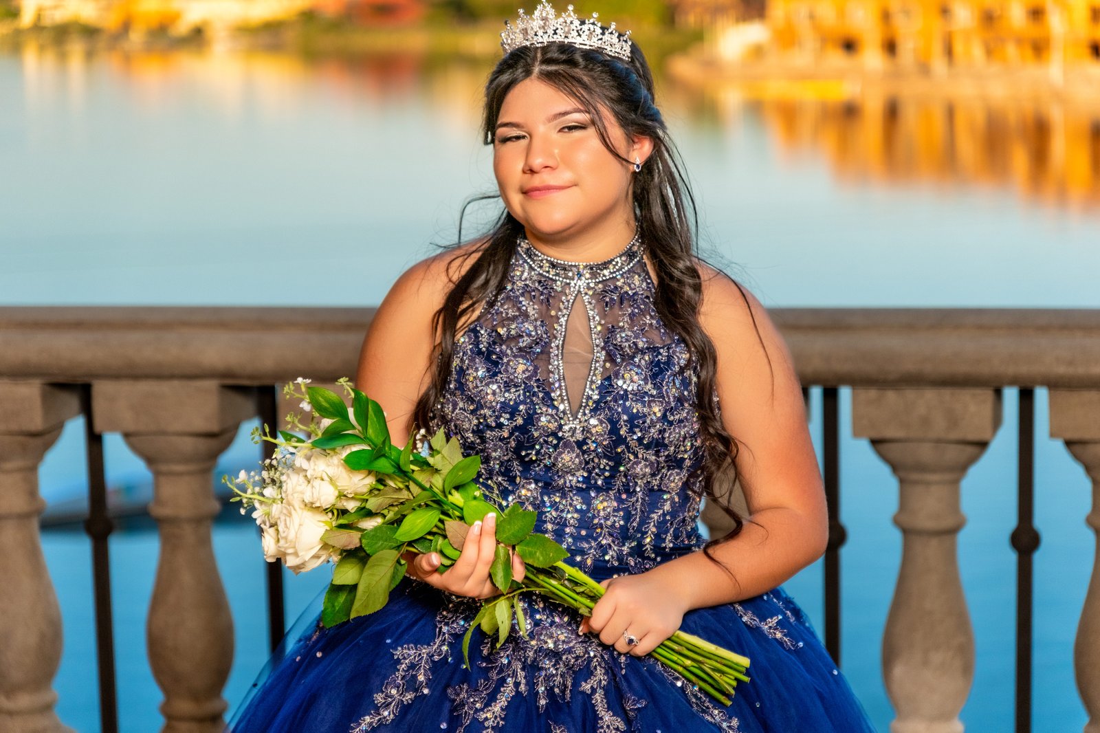 Quinceañera holding a bouquet beside the water