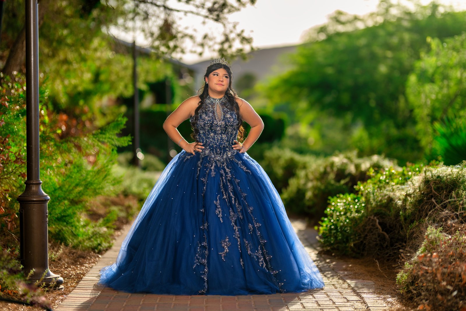 Quinceañera portrait in a blue gown on a garden path