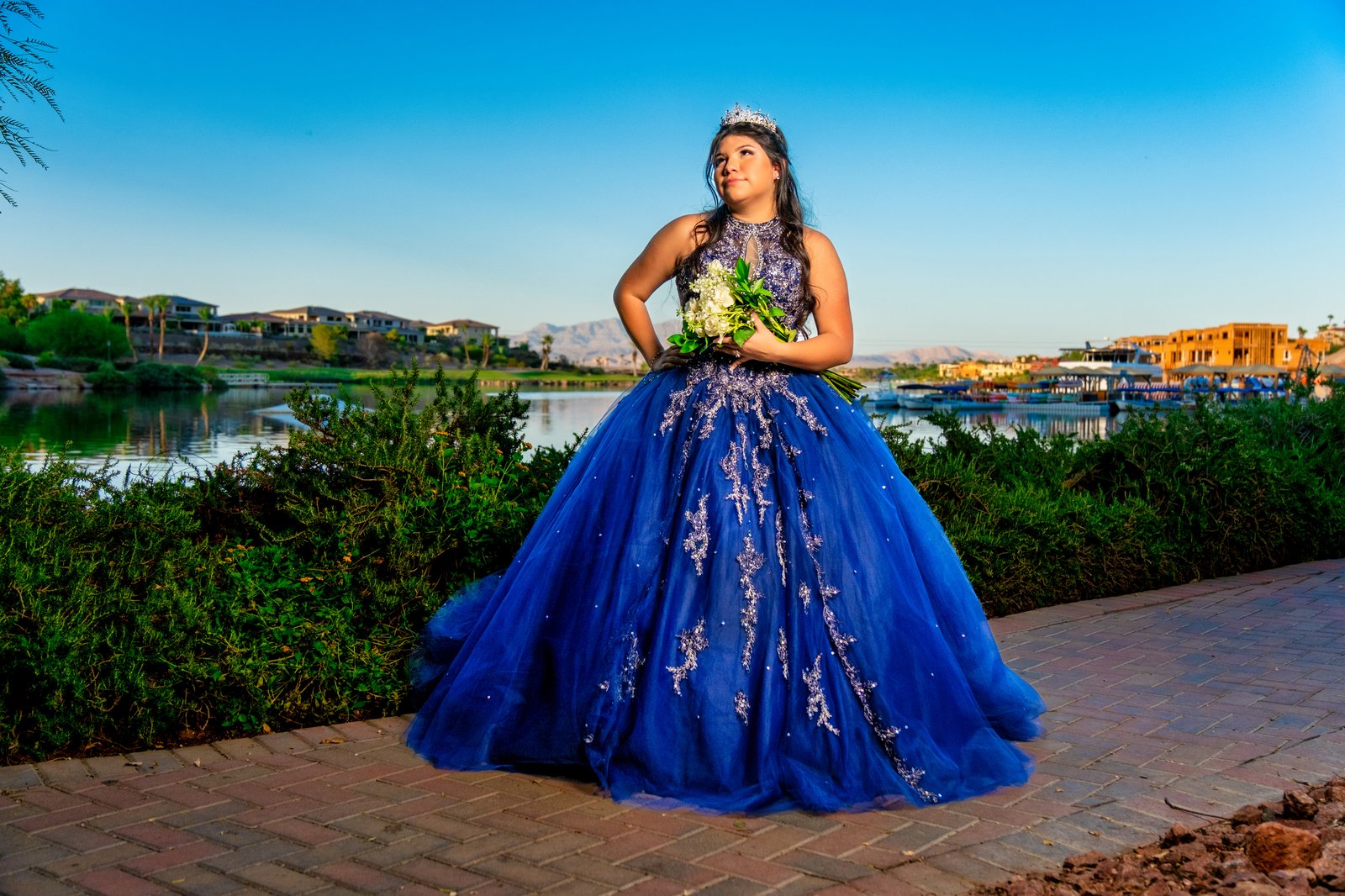 Quinceañera in a blue gown beside the lake at golden hour